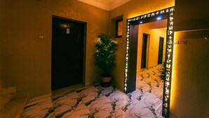 A hallway with a potted plant, a door, and a wall with illuminated text. - Pyramid-view retreat walk there in minutes (Cairo Governorate)