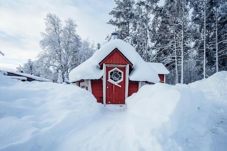 A red wooden cabin surrounded by snow-covered trees.. Hotell Fjällheim