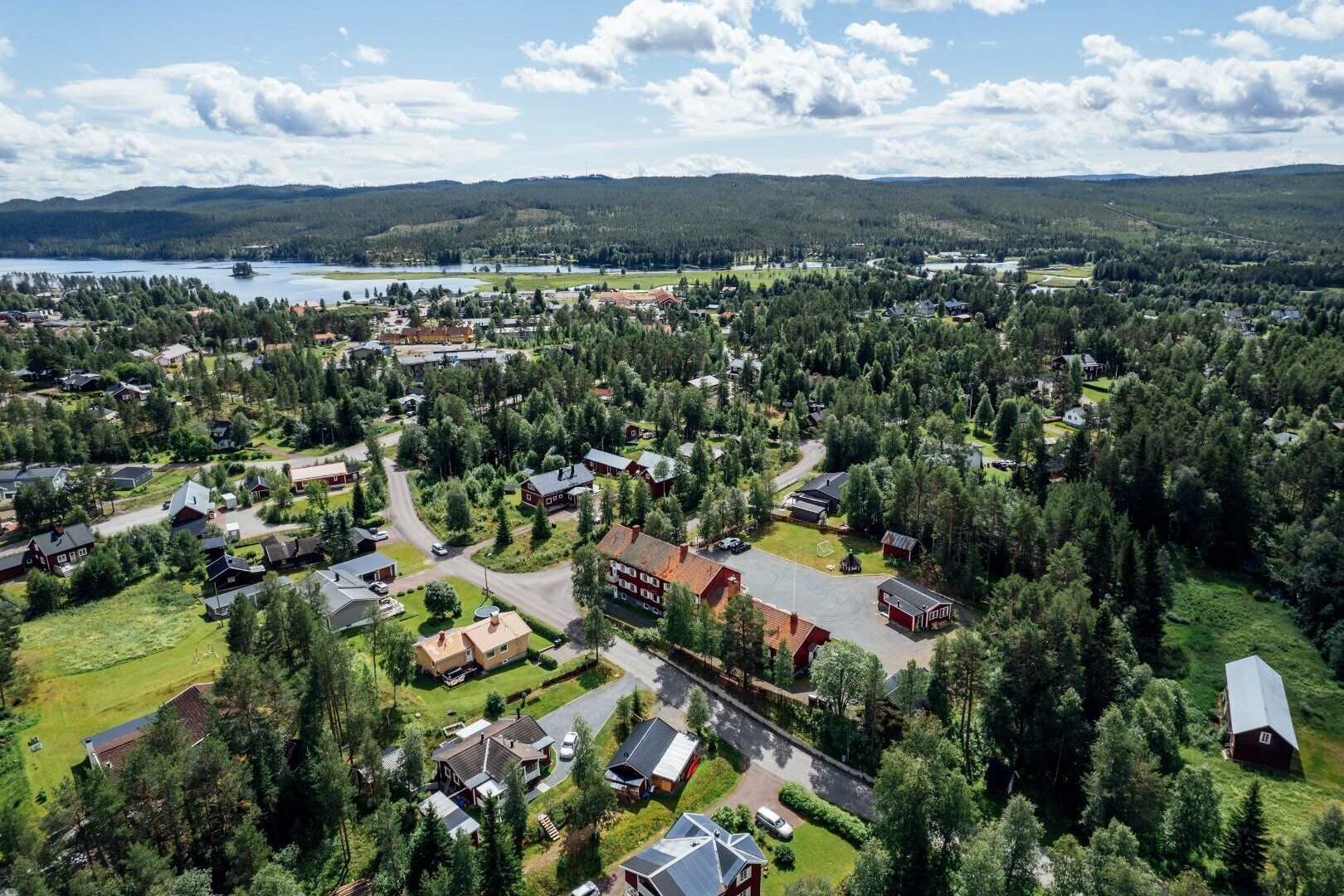 An aerial view of a residential area with houses, roads, and a lake in the background.