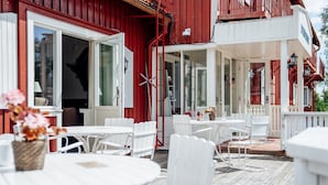 A red building with white exterior walls, large windows, and a covered outdoor seating area with white tables and chairs. - Hotell Fjällheim (Idre)