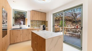 Une cuisine moderne avec des meubles en bois, un plan de travail en marbre et une machine à café.
