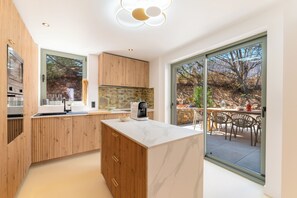 A modern kitchen with wooden cabinets, a marble countertop, and a coffee machine. - VILLA 6 BEDROOMS 7 BATHROOMS WITH SWIMMING POOL Lovely garden with pétanque court. (Sainte-Maxime)