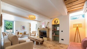 Un salon avec une cheminée, des canapés, une table basse et une lampe.