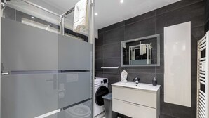 A modern bathroom with a glass shower enclosure, a built-in washing machine, a vanity with a mirror, and a towel rack. - Apt With Terrace and sea View, 2min From the Beach (Antibes)