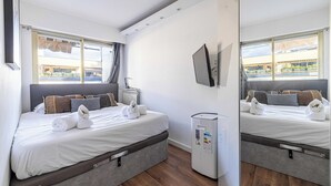 A hotel room with a bed, a flat-screen TV, a heater, and a view of the outside. - Apt With Terrace and sea View, 2min From the Beach (Antibes)