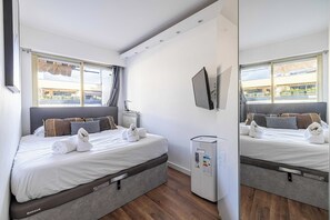 Ein Hotelzimmer mit Bett, Flachbildfernseher, Heizung und Blick ins Freie.