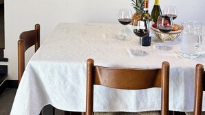 Un coin repas avec une table dressée pour deux personnes, un escalier agrémenté d’une rampe décorative et un téléviseur en arrière-plan.