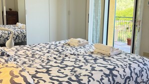 Une chambre à coucher avec un lit, une armoire, un miroir et un balcon offrant une vue.