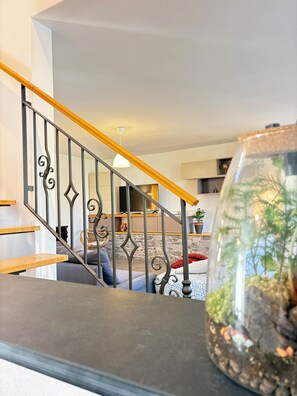 Eine Treppe mit einer Holzhandläufe, eine Glasvase mit Pflanzen und eine Steinwand im Hintergrund.