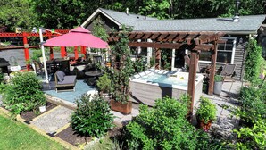 Een achtertuin met een jacuzzi, terrasmeubilair en een pergola.