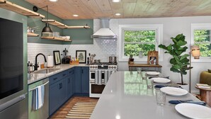 Een moderne keuken met een centraal eiland, een inbouwoven en een houten plafond.