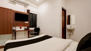 A hotel room with a bed, desk, chair, air conditioning unit, and a mirror. - Classic Yuva Inn (Nagpur)