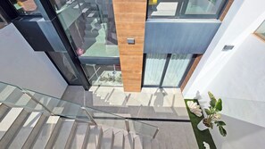 A modern interior with a glass staircase, a wooden accent wall, and a potted plant. - Villa Benidorm - Private swimming pool with sea views (VC)