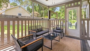 A covered patio with outdoor furniture, a ceiling fan, and a view of a house in the background. - Ramblewood Large Fenced Yard Pets (Mt Pleasant)