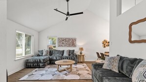 A modern living room with a sectional sofa, a round coffee table, and a ceiling fan. - Ramblewood Large Fenced Yard Pets (Mt Pleasant)