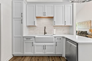 Une cuisine moderne avec des meubles blancs, un îlot central et un lave-vaisselle.