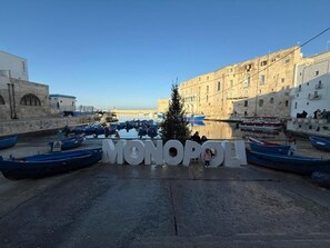 A waterfront area with boats docked, a large sign spelling 'MONOPOLI', and buildings with stone architecture. - AUTHENTIC TRULLI VILLA WITH A PRIVATE POOL AND PANORAMIC VIEWS IN MONOPOLI (Puglia)