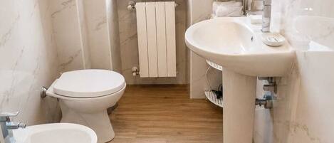 A compact bathroom with a toilet, bidet, and sink.