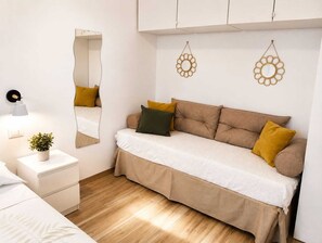 Ein modernes Schlafzimmer mit Schlafsofa, Nachttischen, einem Spiegel und dekorativen Wandgestaltungen.