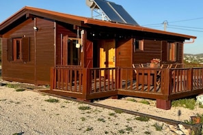 A wooden cabin with a balcony, a door, and a small porch area.