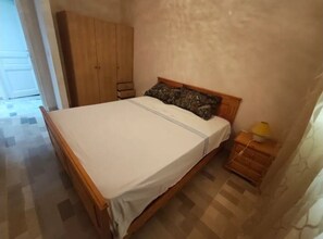 Une chambre à coucher avec un lit en bois, une armoire et une table de chevet.