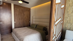 Een slaapkamer met een bed, een plafondventilator, een houten scheidingswand en een lamp.