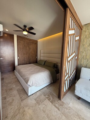 Ein Schlafzimmer mit einem Bett, einem Deckenventilator, einer Holzwand und einer Lampe.