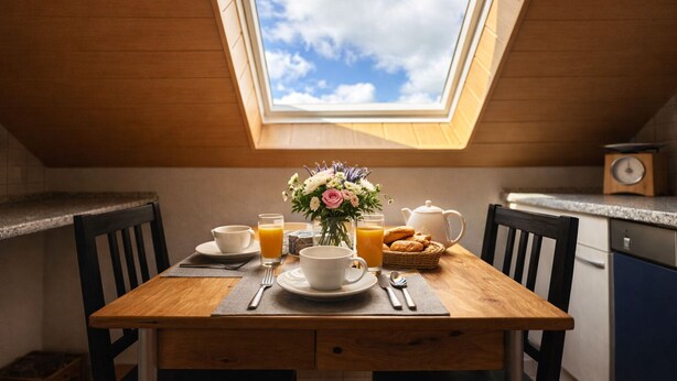 A dining table with breakfast items, a vase of flowers, and a skylight above. - Spacious vacation apartment in a quiet location with lots of nature. Pet friendly! (Tiefenthal)