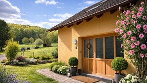 A house with a wooden door, a number '8' sign, a wreath, and a garden with flowers and shrubs. - Spacious vacation apartment in a quiet location with lots of nature. Pet friendly! (Tiefenthal)