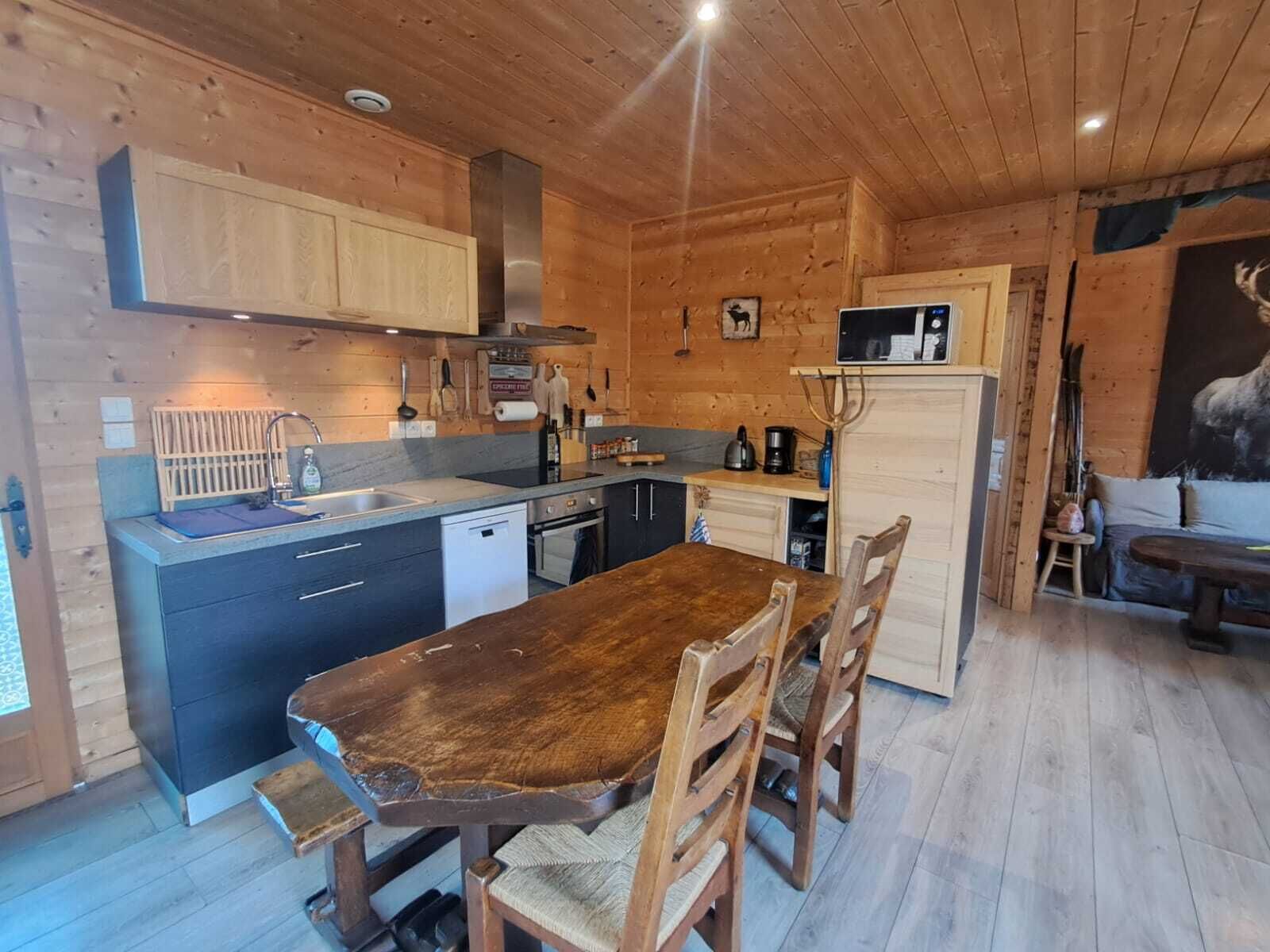 Een houten chalet interieur met een keuken, eethoek en een schilderij van een hert.