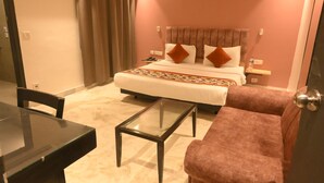 A hotel room with a bed, a desk, a chair, and a sofa. - The Centrum (New Delhi)