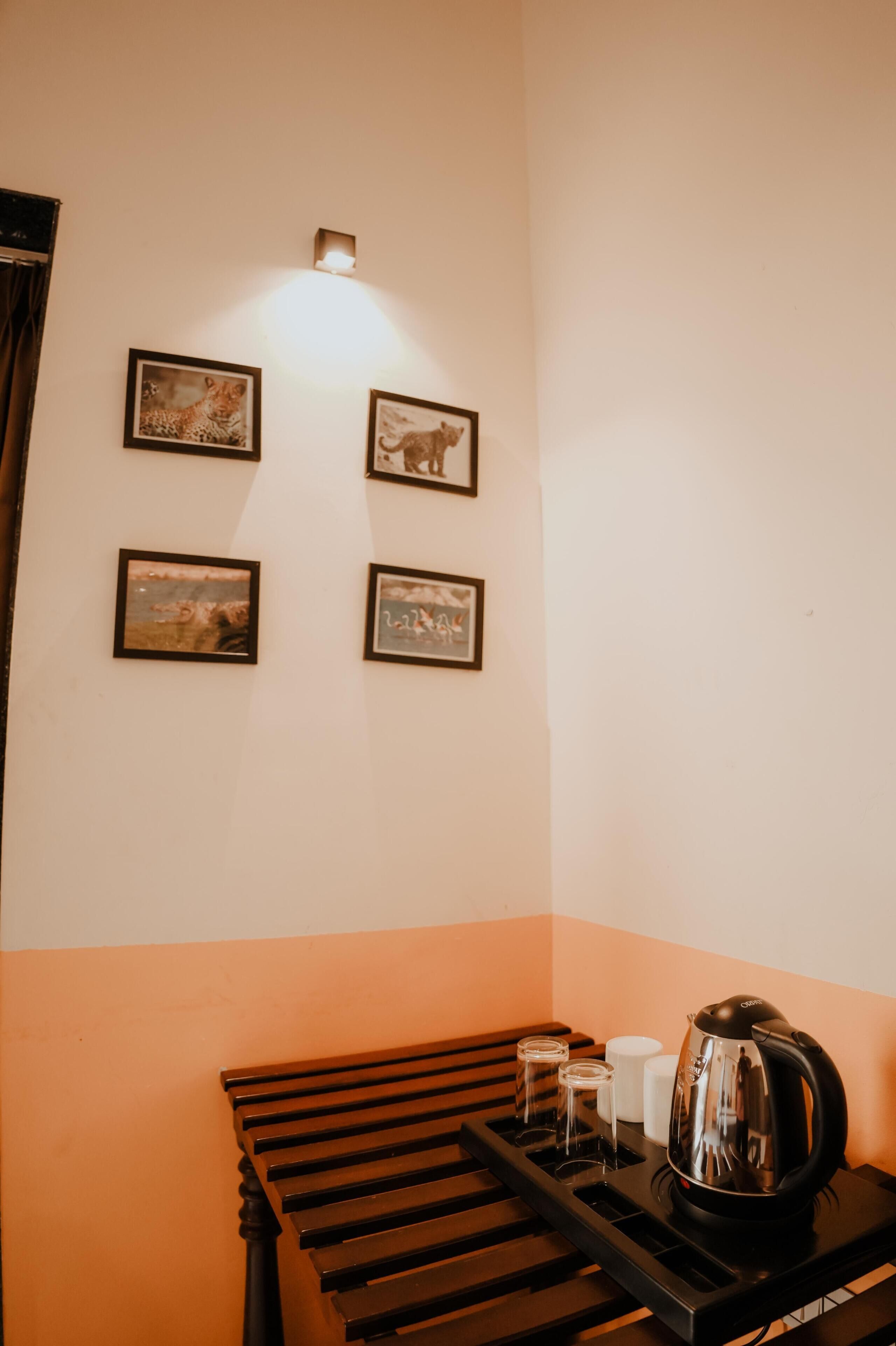 Una habitación con un banco de madera, una tetera y tres cuadros en la pared.