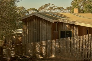 A wooden building with a sloped roof and a fenced yard. - Lay Day House (Lorne)