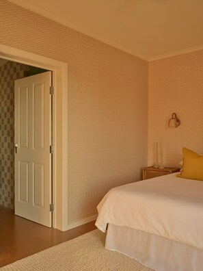 A bedroom with a bed, a nightstand, a lamp, and a door. - Lay Day House (Lorne)