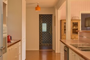 A kitchen with a wooden countertop, a sink, and a hanging orange pendant light. - Lay Day House (Lorne)