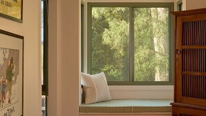 A room with a large window, a wooden bench, and a door. - Lay Day House (Lorne)
