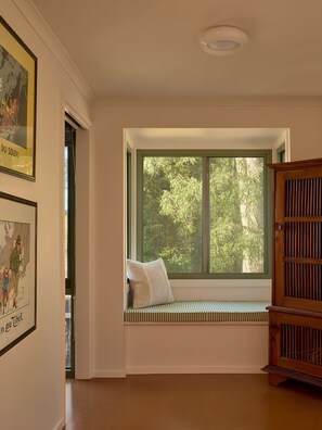 A room with a large window, a wooden bench, and a door. - Lay Day House (Lorne)