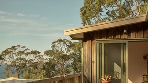 Un bâtiment en bois doté d’un balcon donnant sur une étendue d’eau et des arbres.
