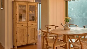 A dining area with a wooden cabinet, wicker chairs, and a table with a vase. - Lay Day House (Lorne)