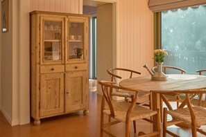 A dining area with a wooden cabinet, wicker chairs, and a table with a vase. - Lay Day House (Lorne)