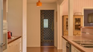 Een smalle keuken met een zwart-wit betegelde achterwand, houten kastjes en een hangende lamp.