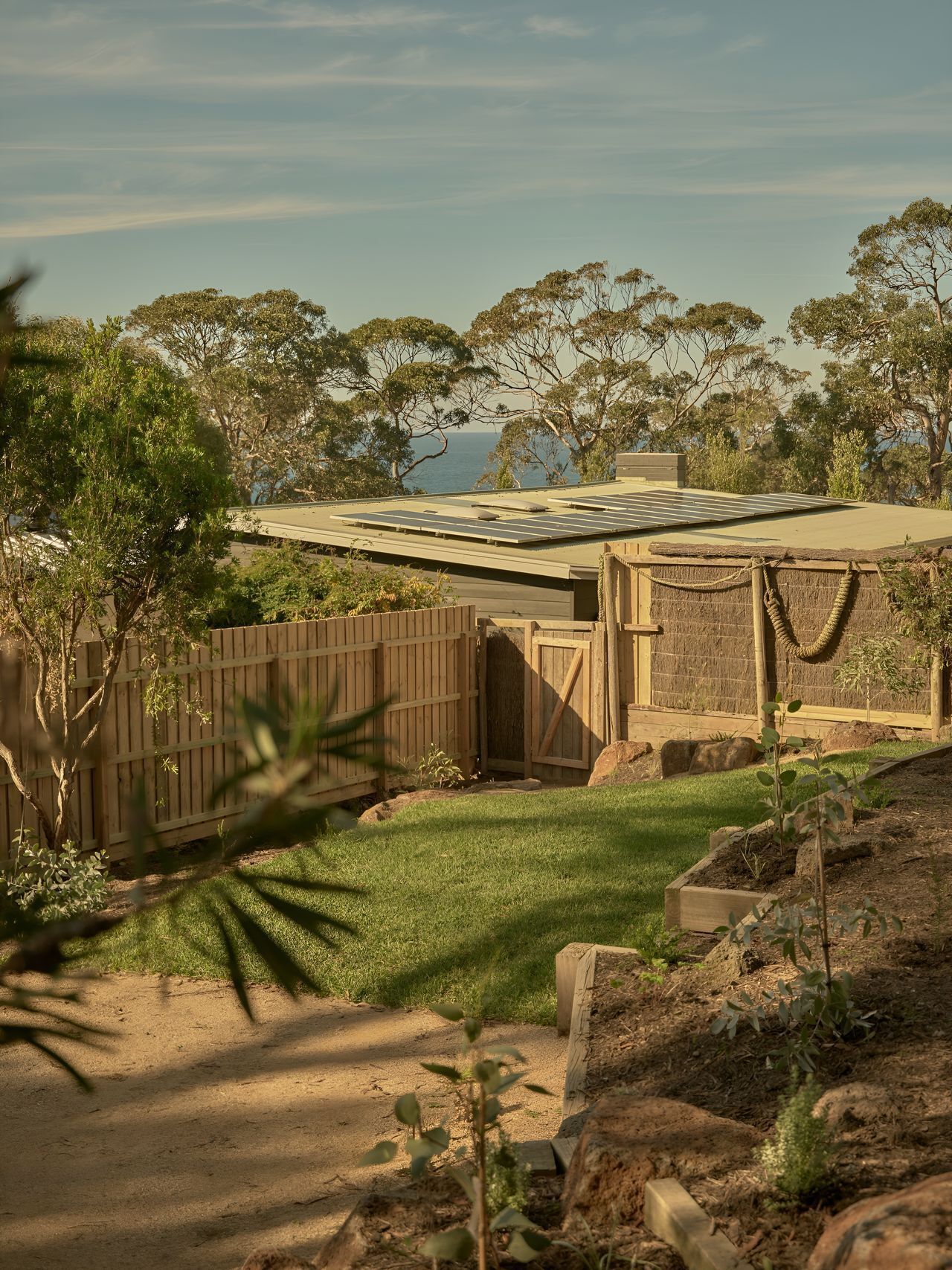 A residential property with a solar panel roof, a fenced yard, and a view of the sea.
