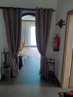 A hallway with curtains, a fire extinguisher, and a blue-framed window. - Cosy alpine house, Adults only (Mitterberg - St. Martin)