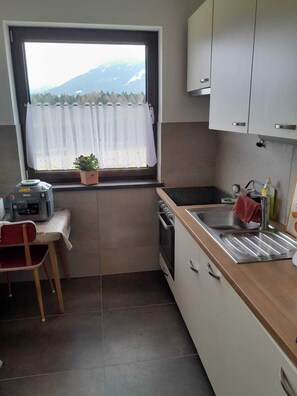 A compact kitchen with a window, a sink, a stove, and a chair. - Cosy alpine house, Adults only (Mitterberg - St. Martin)