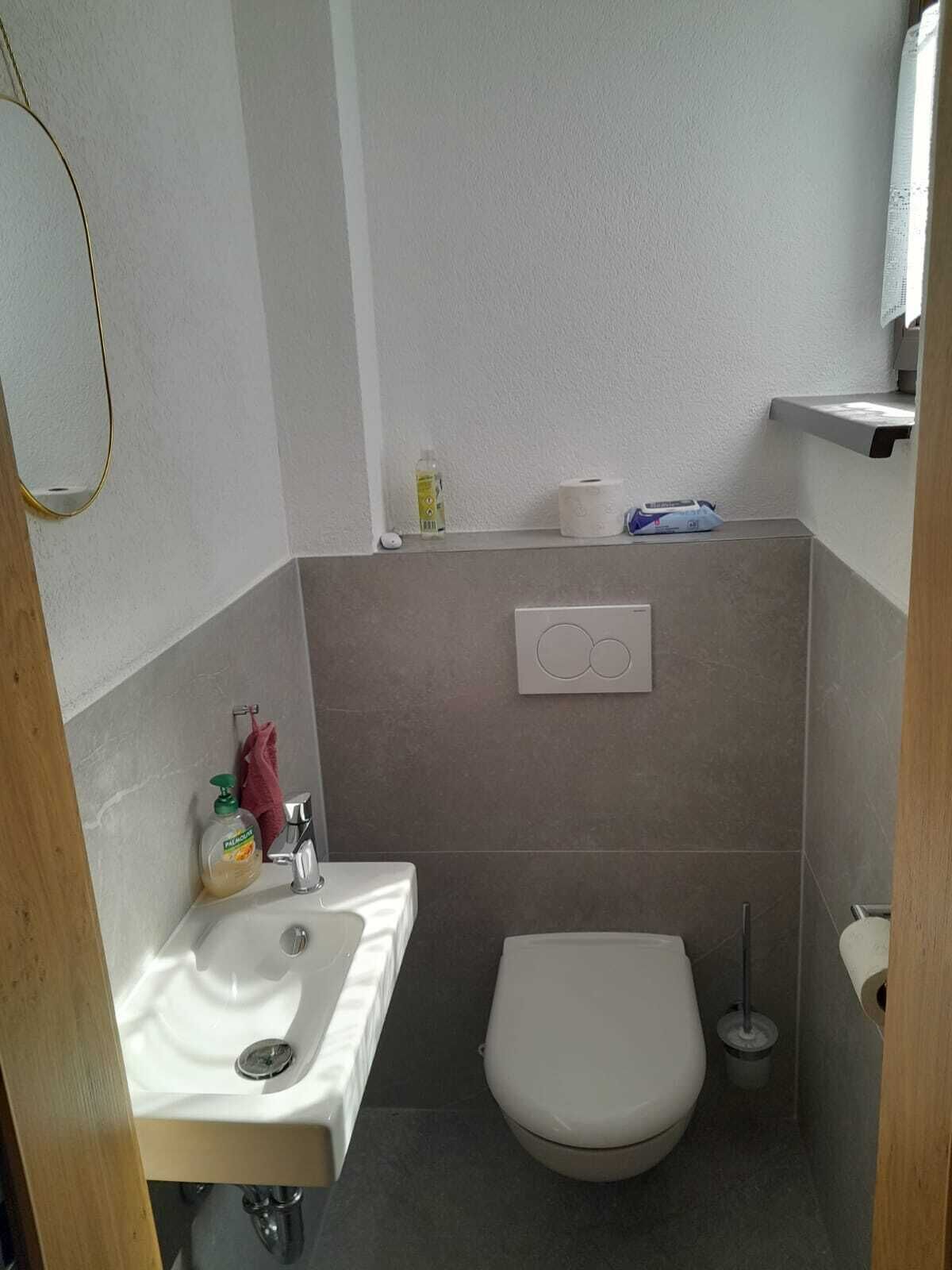 A small bathroom with a sink, toilet, and a towel dispenser.