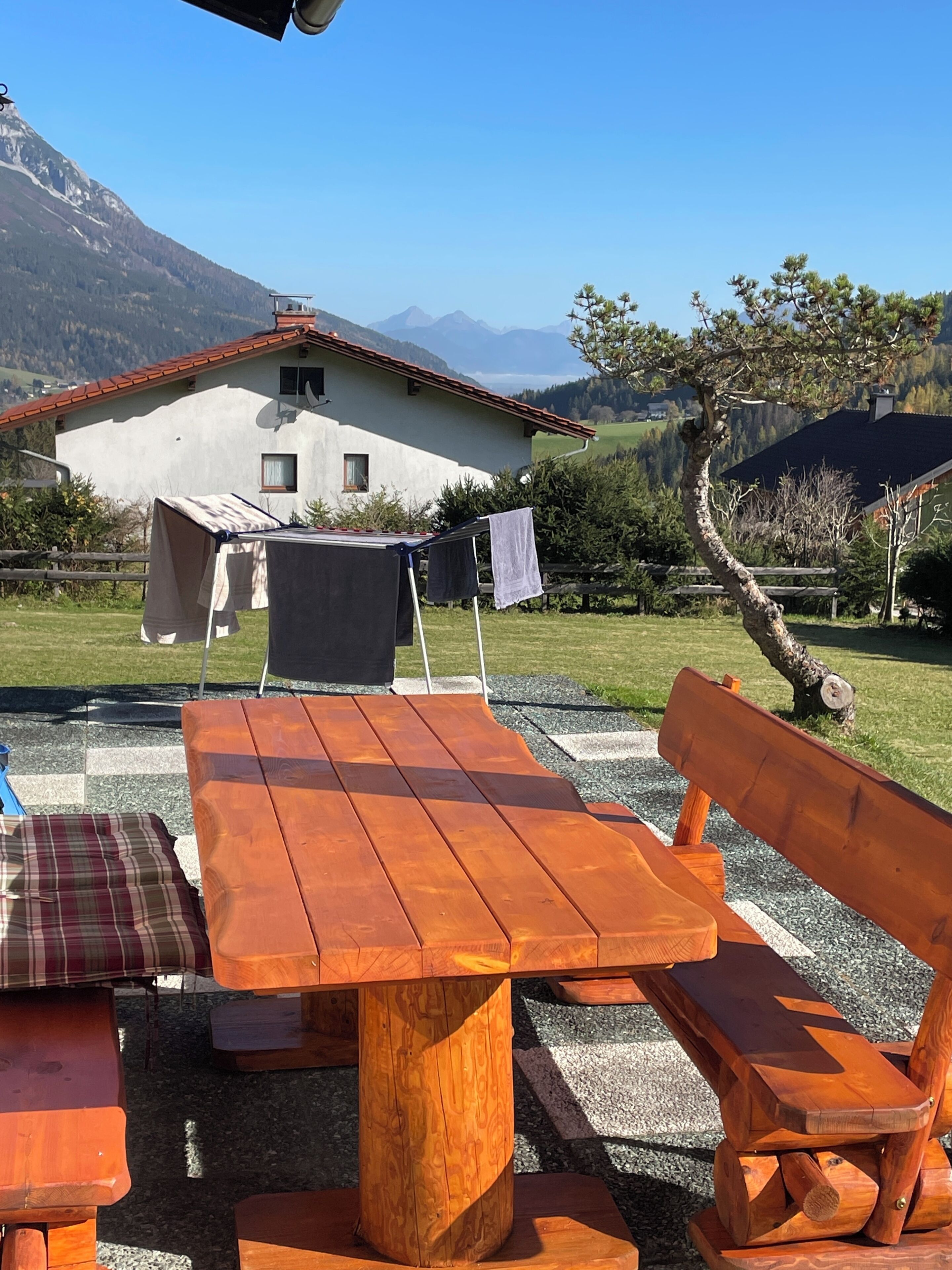 Ein Holztisch mit Bänken in einer Außenumgebung mit Blick auf die Berge.