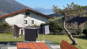 Mesa y bancos de madera en un entorno al aire libre, con vista a la montaña.