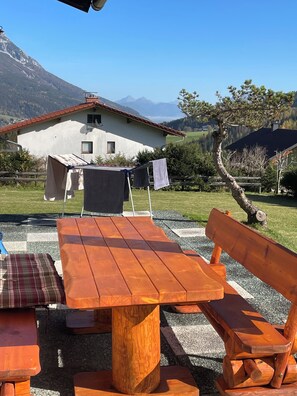 A wooden table and benches in an outdoor setting with a mountain view. - Cosy alpine house, Adults only (Mitterberg - St. Martin)