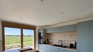 Una cucina moderna con un piano di lavoro in legno, mobili azzurri e vista su un campo verde.