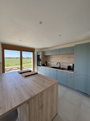 Eine moderne Küche mit Holzarbeitsplatte, hellblauen Schränken und Blick auf ein grünes Feld.